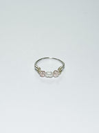 Silver wrapped Ring with Pearl in the middle and two pink beads on two sides on a white background.