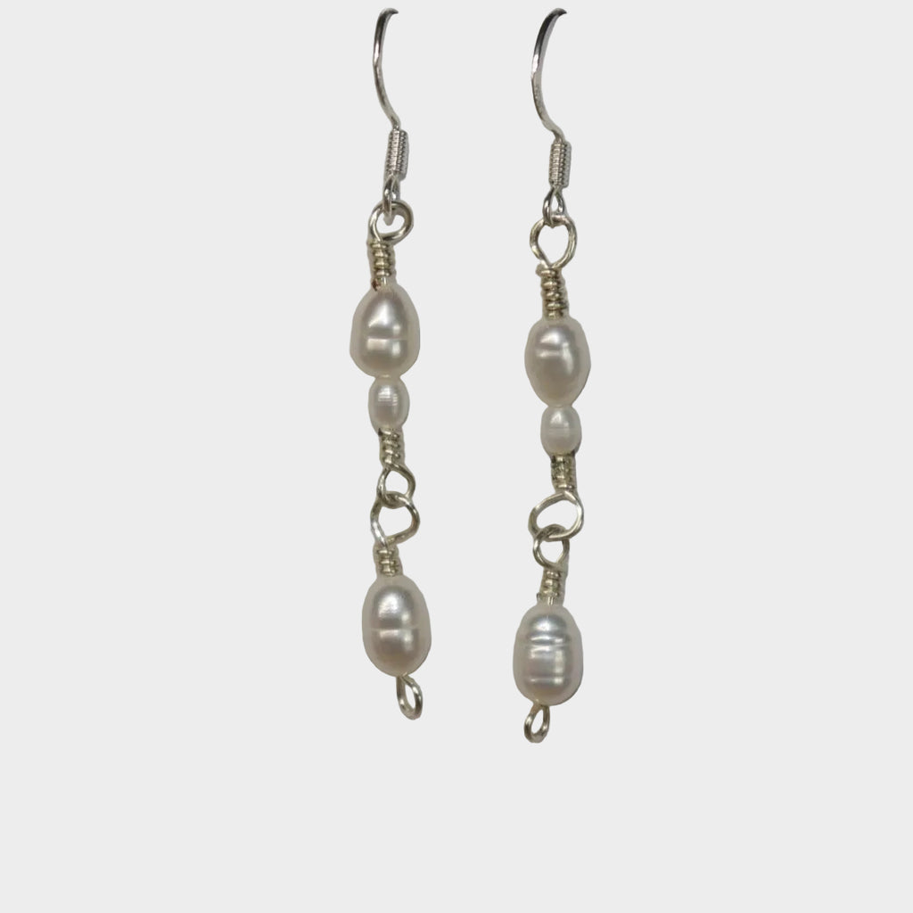 Pair of pearl link earrings on a gray background