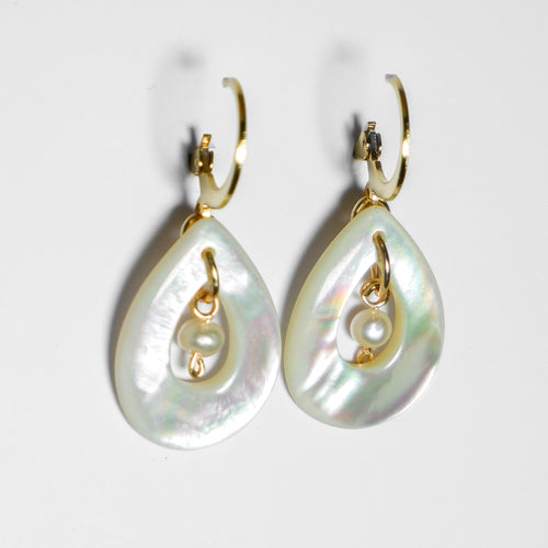 An ultra-close up side shot of gold earrings with teardrop-shaped mother of pearl with pearl in the middle on a white background.