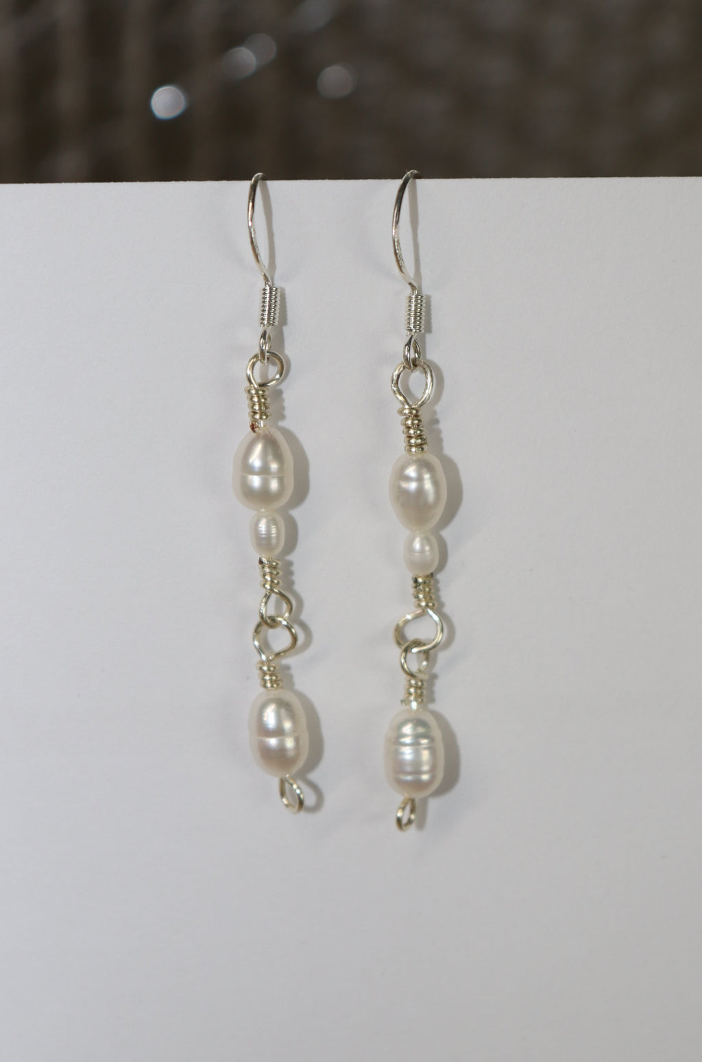 Classic Pearl Link earrings with a white backdrop, and a grey-ish background/