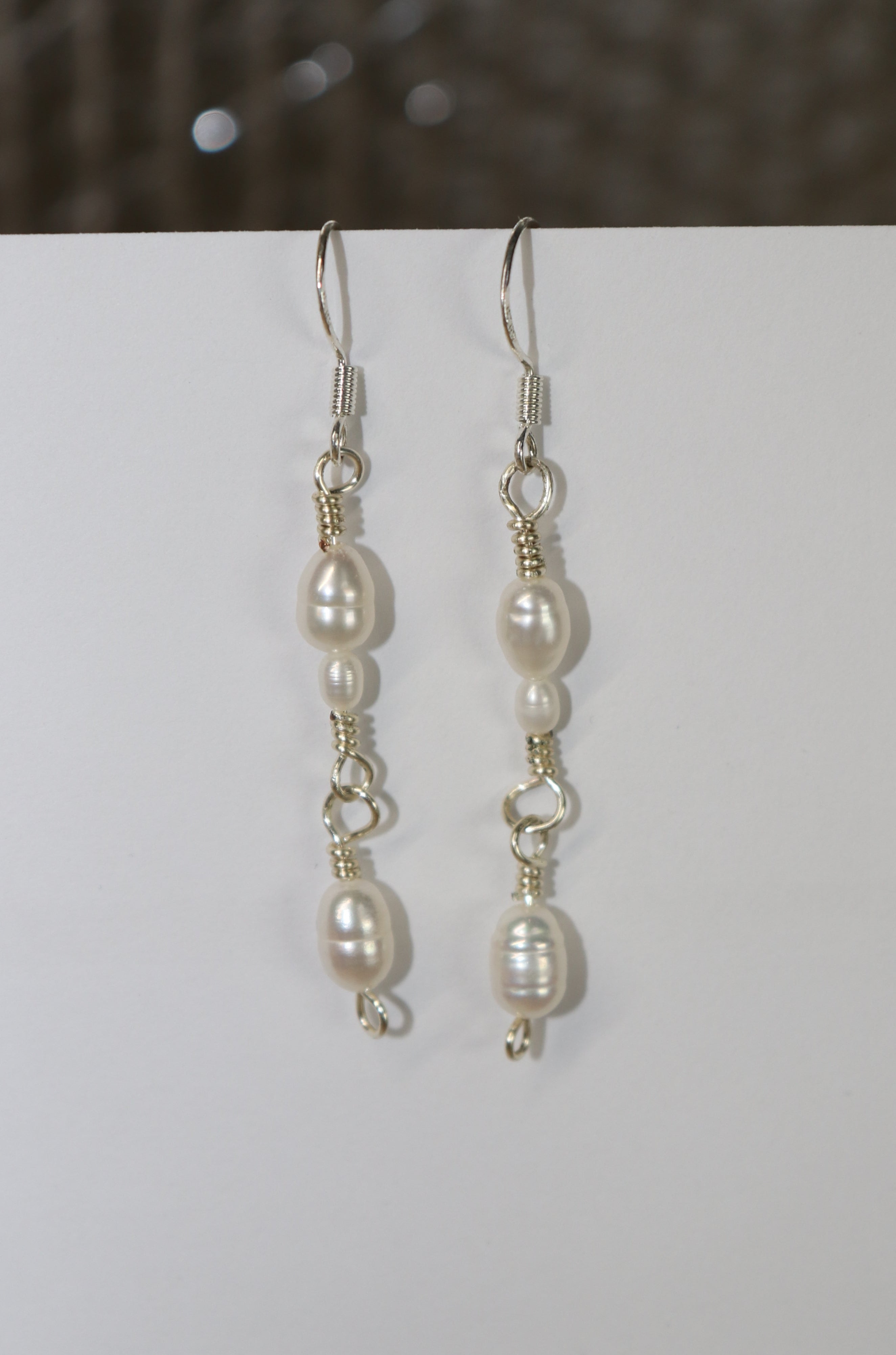 Classic Pearl Link earrings with a white backdrop, and a grey-ish background/