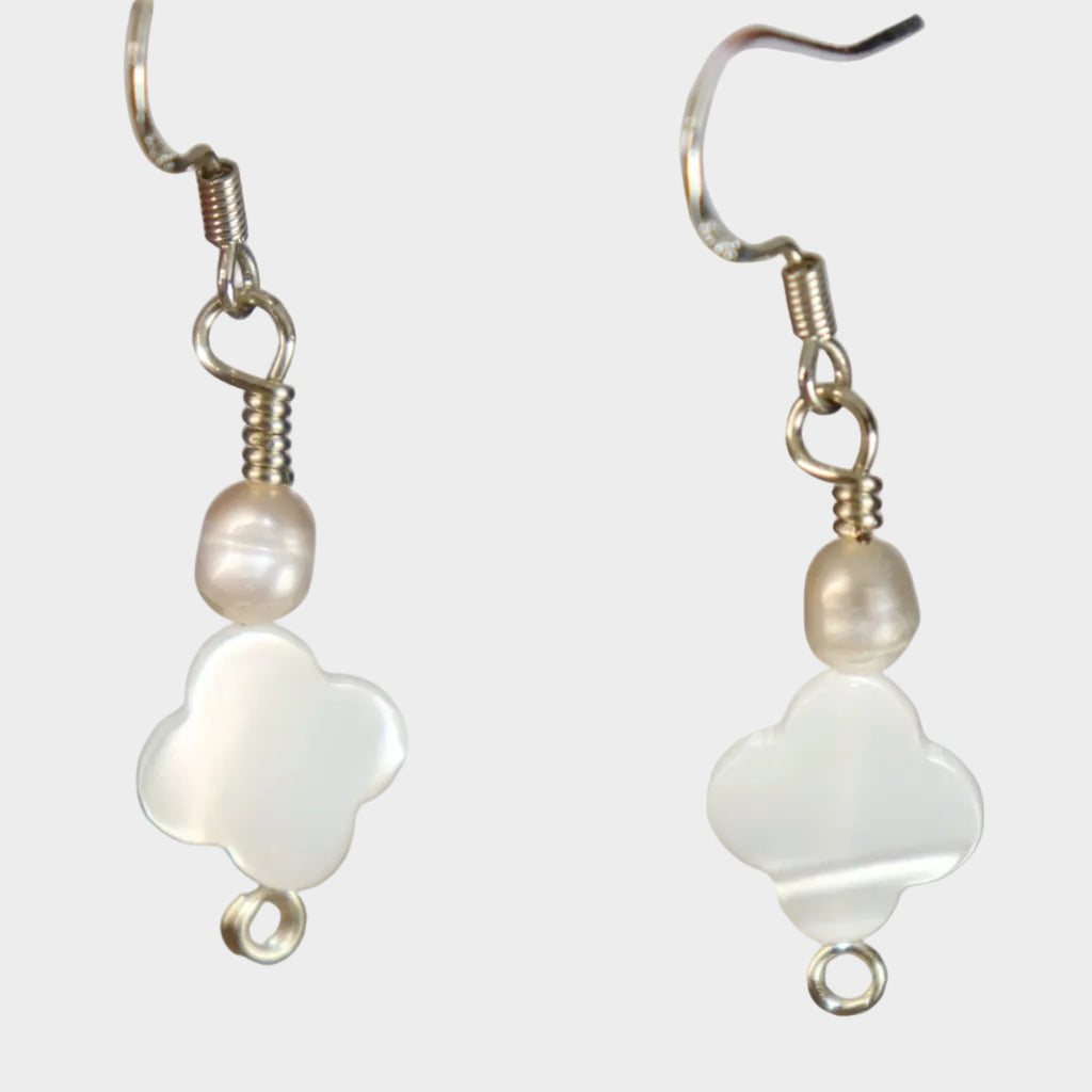 Pair of silver earrings with white clover designs made from mother of pearl and pearl on a white-ish background.