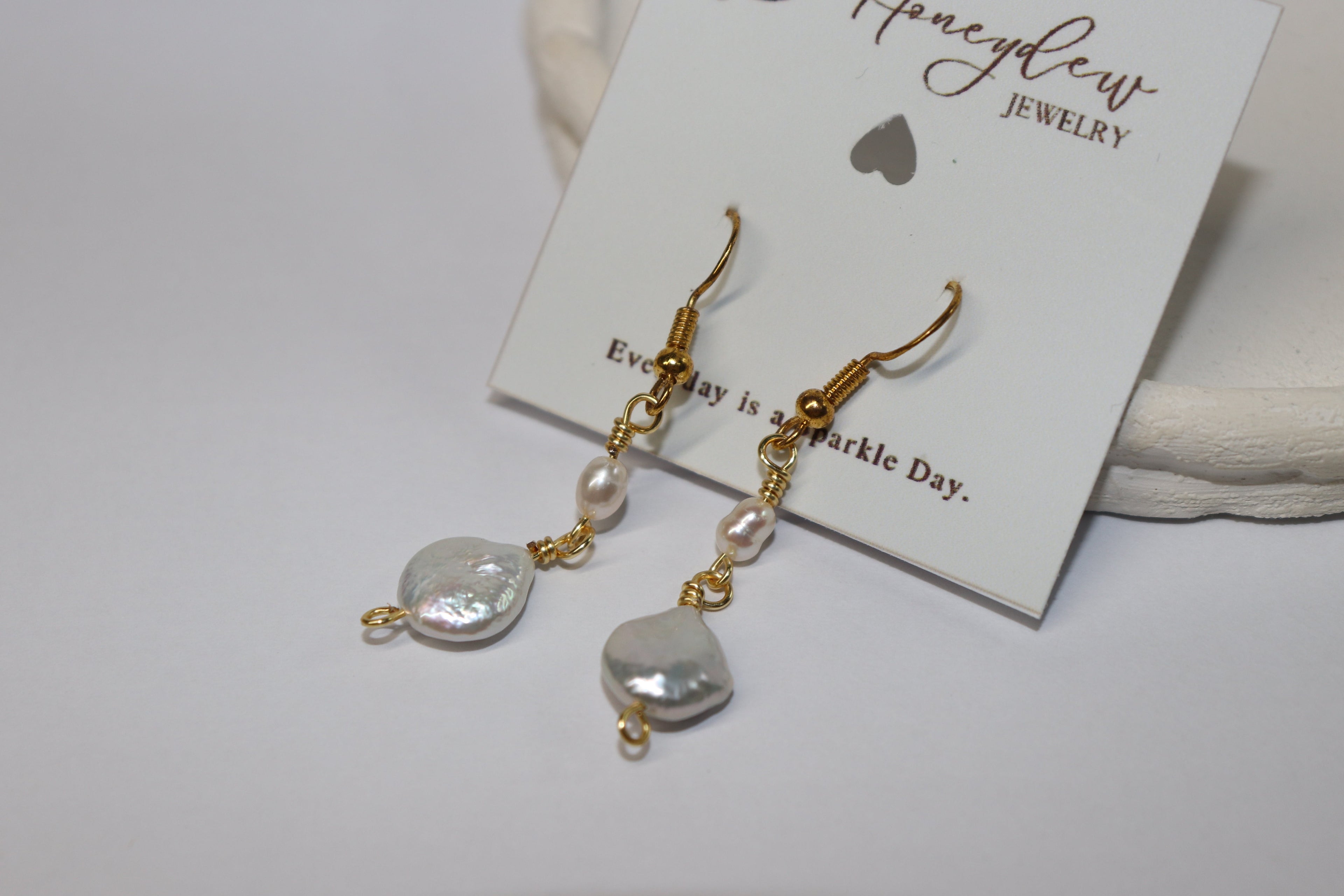 Pearl and gold earrings on a Honeydew Jewellery card with a white background