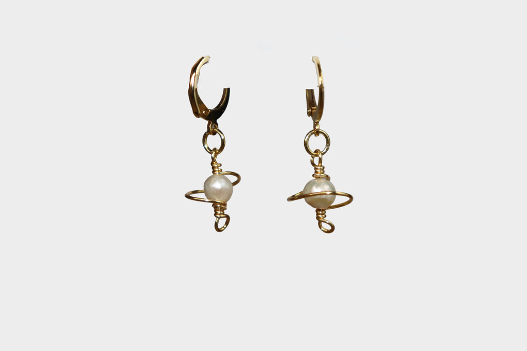 Gold galaxy-like body pearl earrings on a white background.
