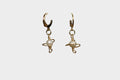 Gold galaxy-like body pearl earrings on a white background.