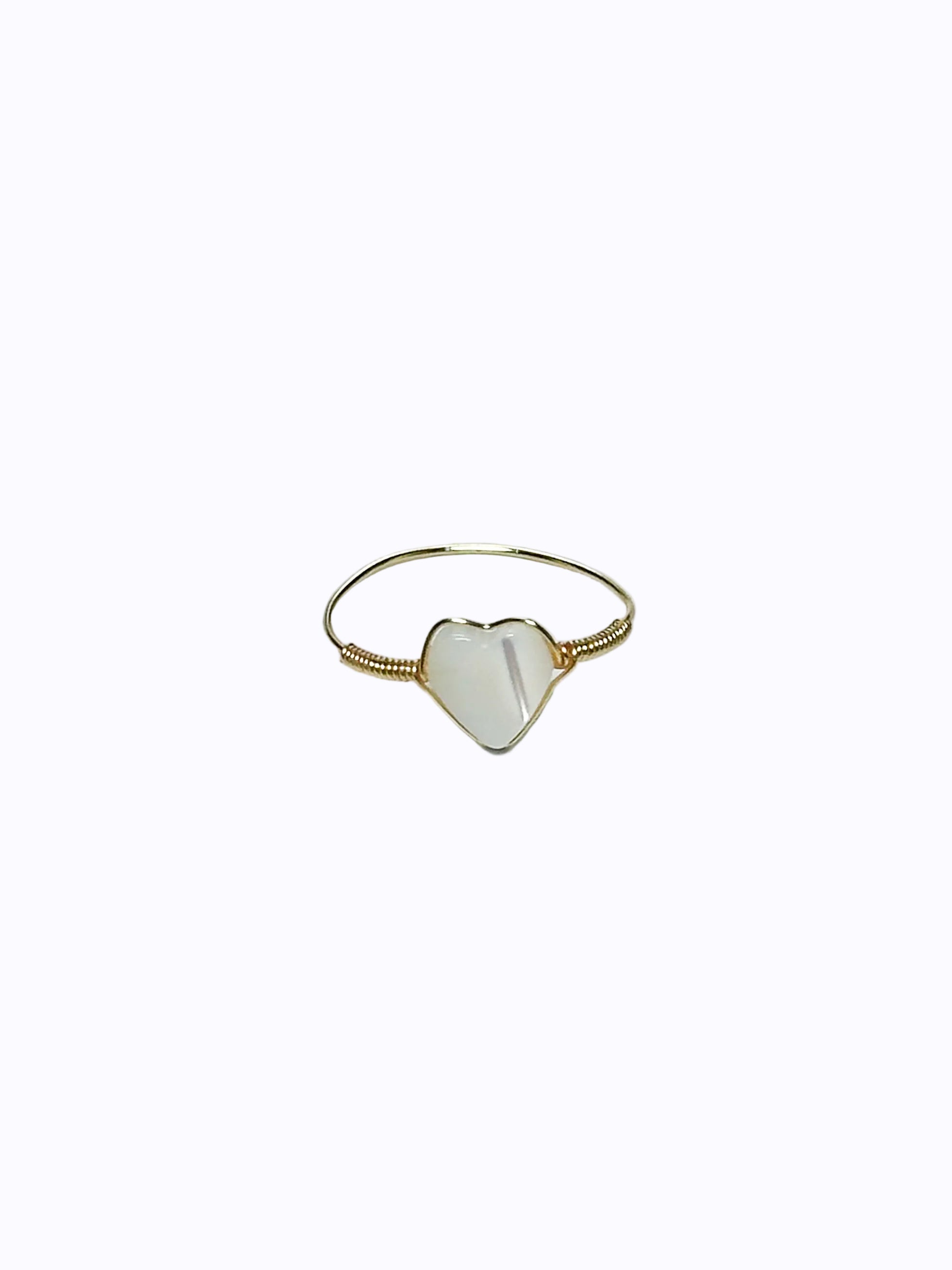 Gold wrapped ring with heart-shaped mother of pearl in the middle on a white background.