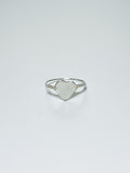Silver wrapped ring with a heart-shaped mother of pearl on a white background with shadows.
