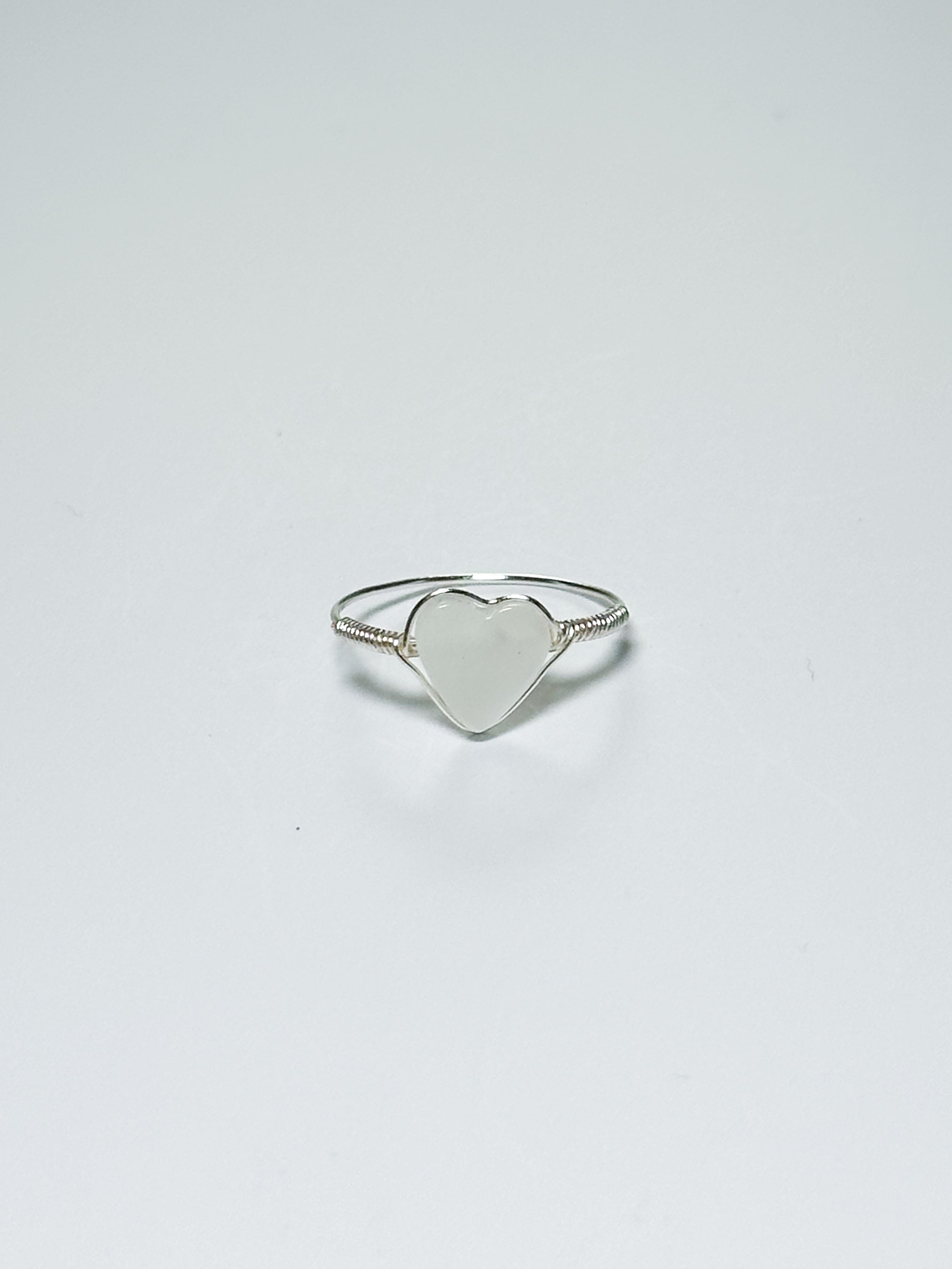 Silver wrapped ring with a heart-shaped mother of pearl on a white background with shadows.