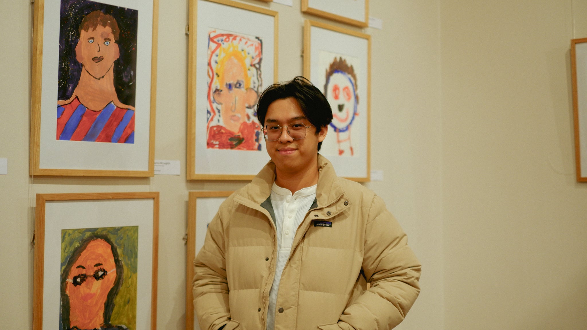 Portrait of the co-founder Jamie Le under yellow lights and children's paintings in the background.