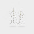 Silver pearl earrings that resemble a jellyfish on a light grey background