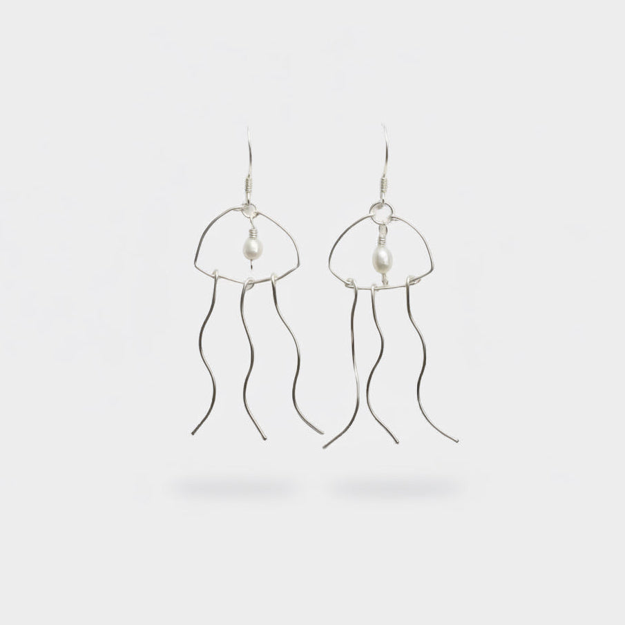 Silver pearl earrings that resemble a jellyfish on a light grey background