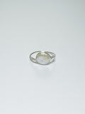 A silver wrapped ring with oval-shaped pearl in the middle on a white background with shadows.