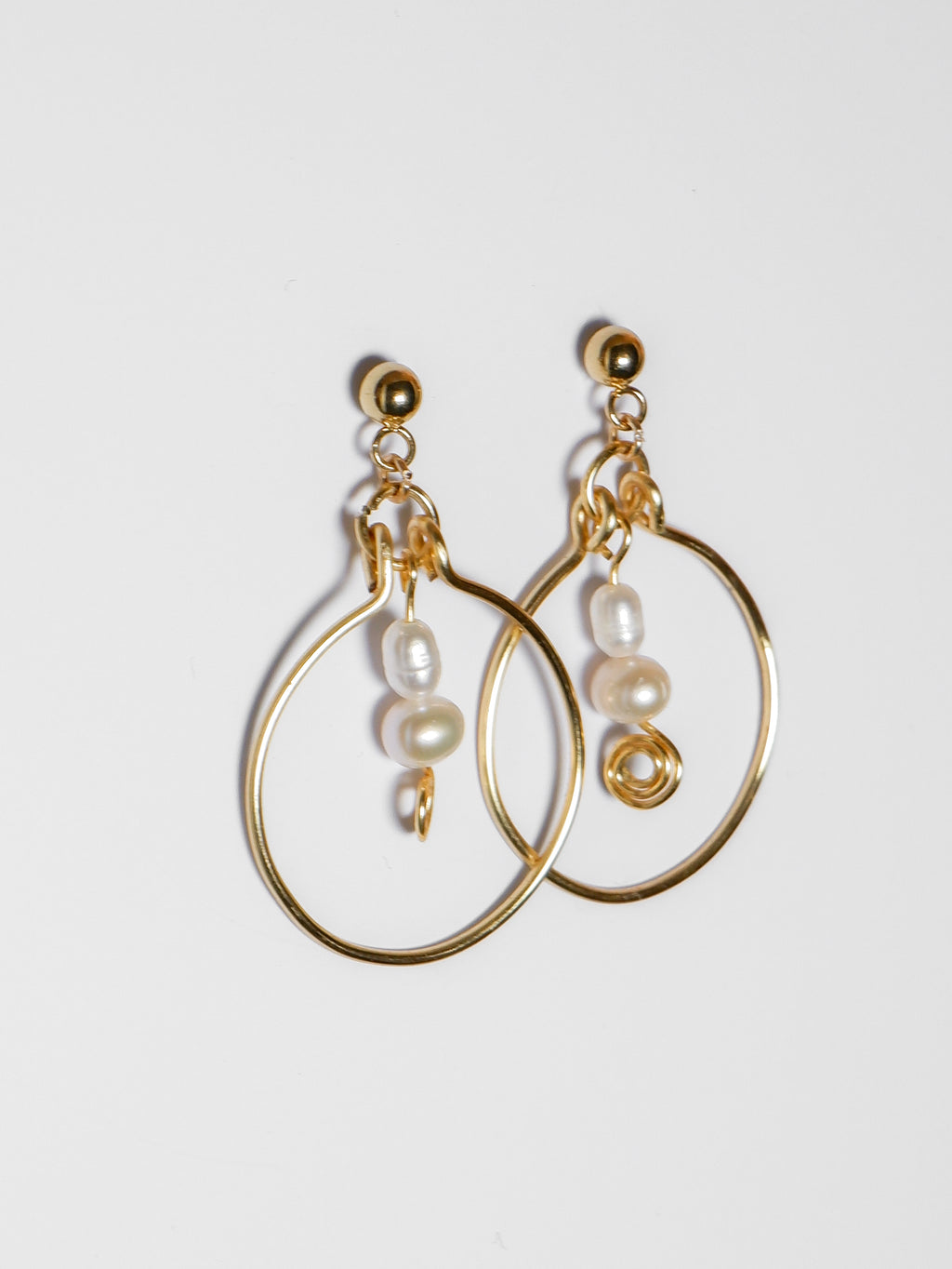 A left-sided shot of a Gold hoop pearl earrings on a white background.