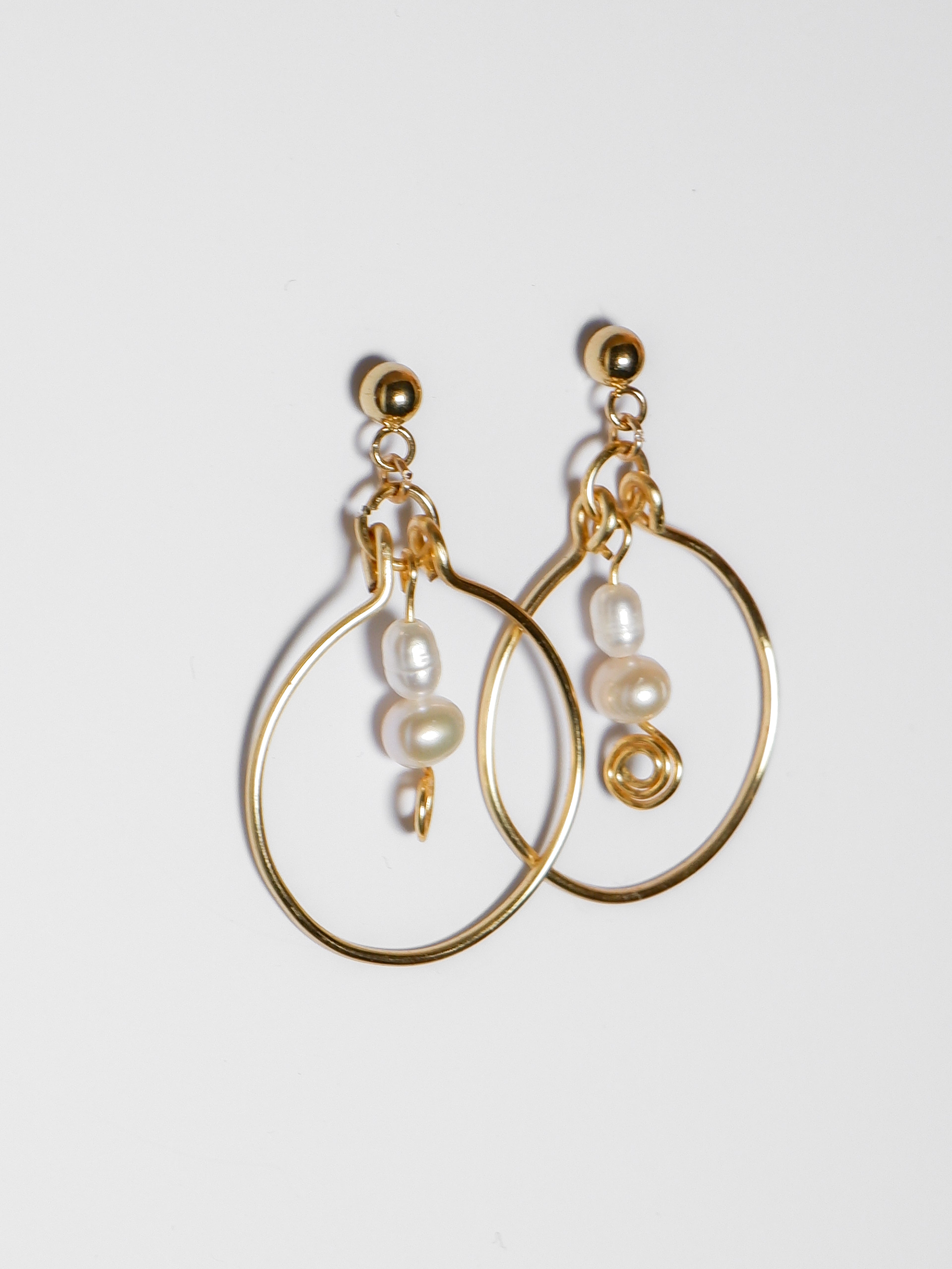 A left-sided shot of a Gold hoop pearl earrings on a white background.