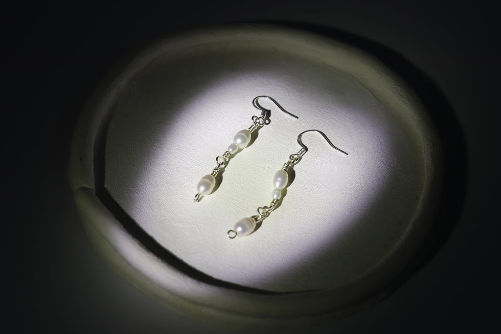 Pearl link earrings on a dark background with a spotlight effect