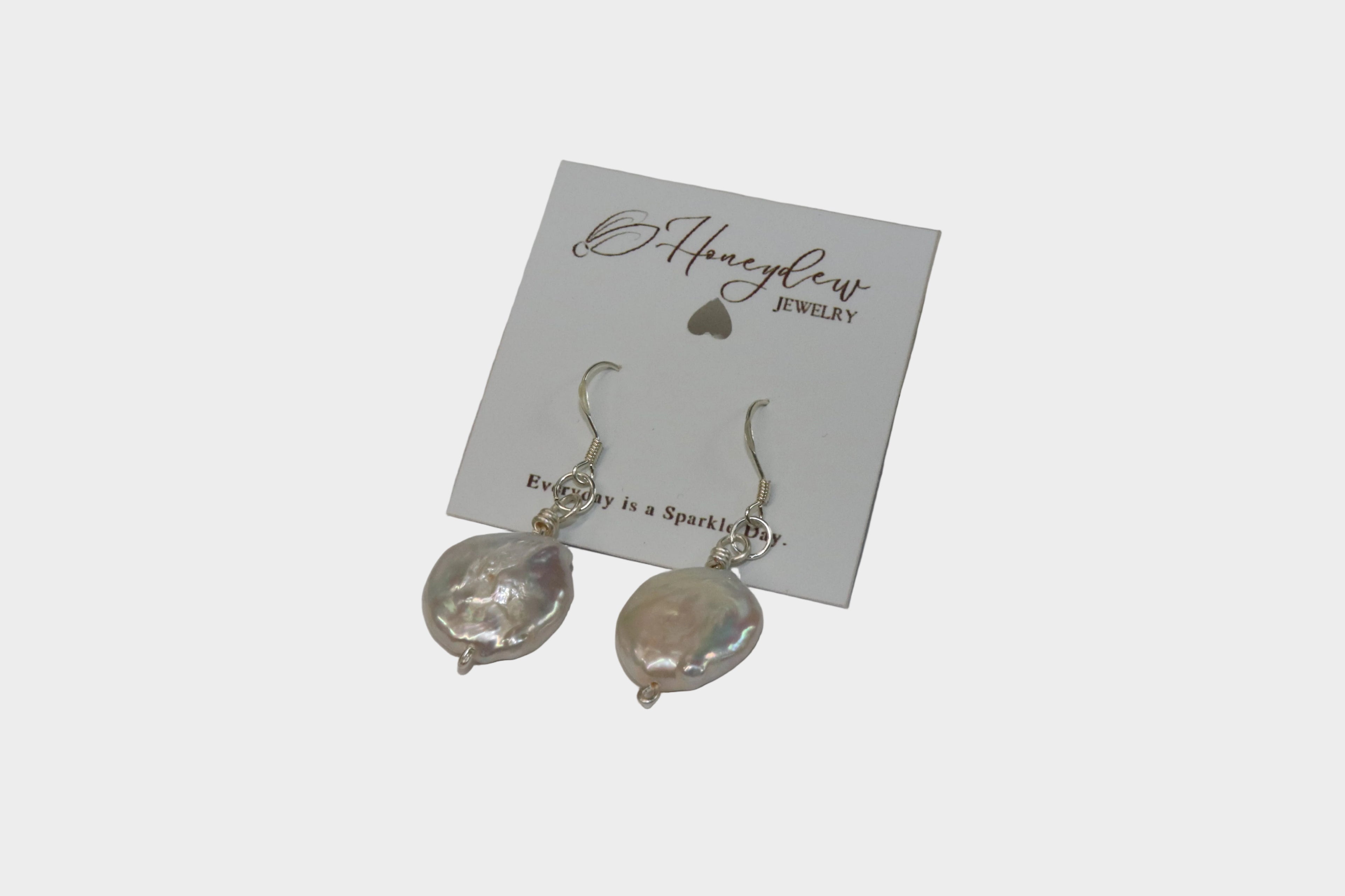 Silver Earrings with Plate-shaped pearls on the end, on a "Honeydew Jewellery" packaging card, with a white background.