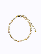 Pearl, pink beads, and gold bracelet on a white background