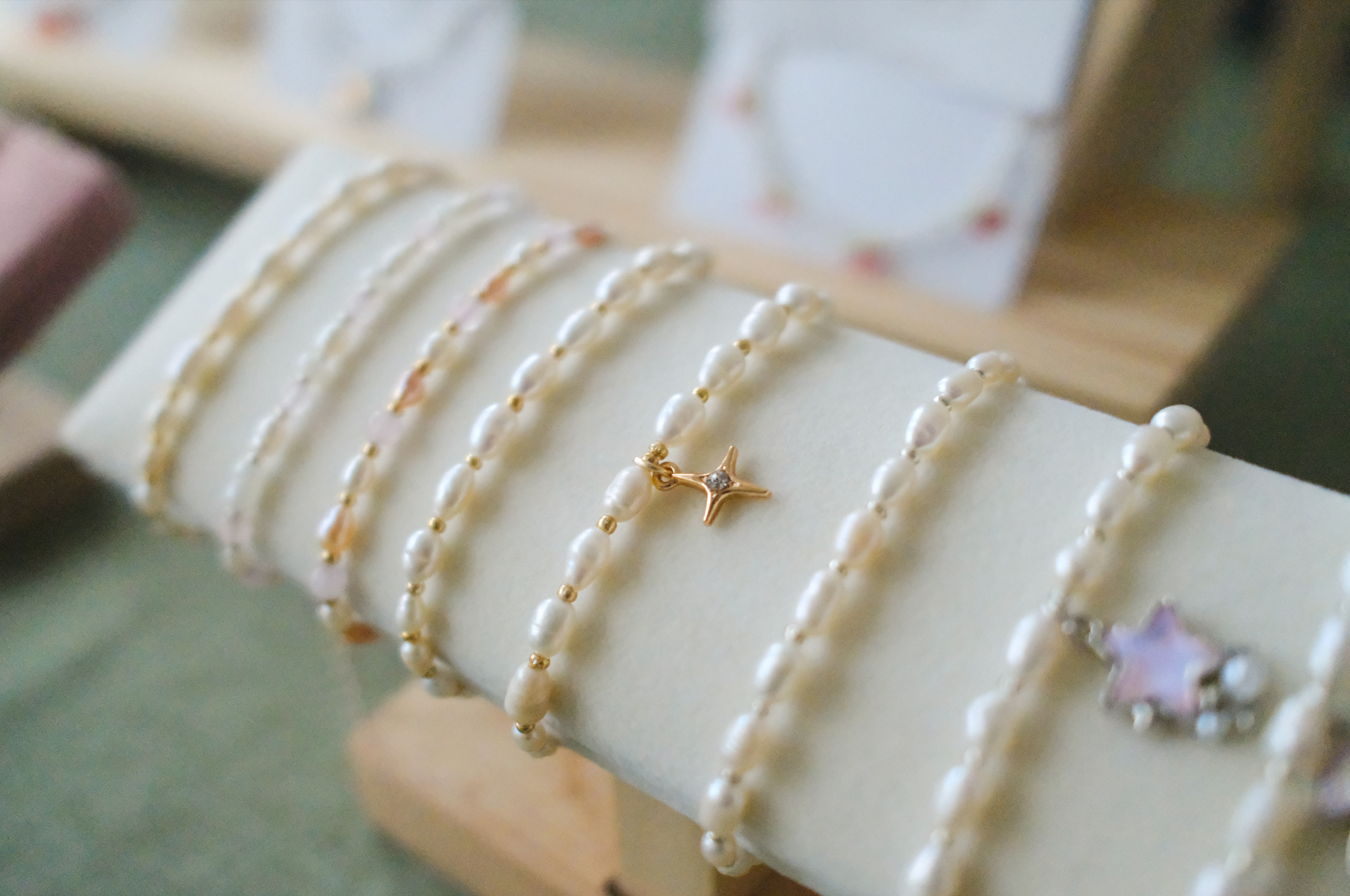 Pearl bracelets with star and flower charms on a white surface