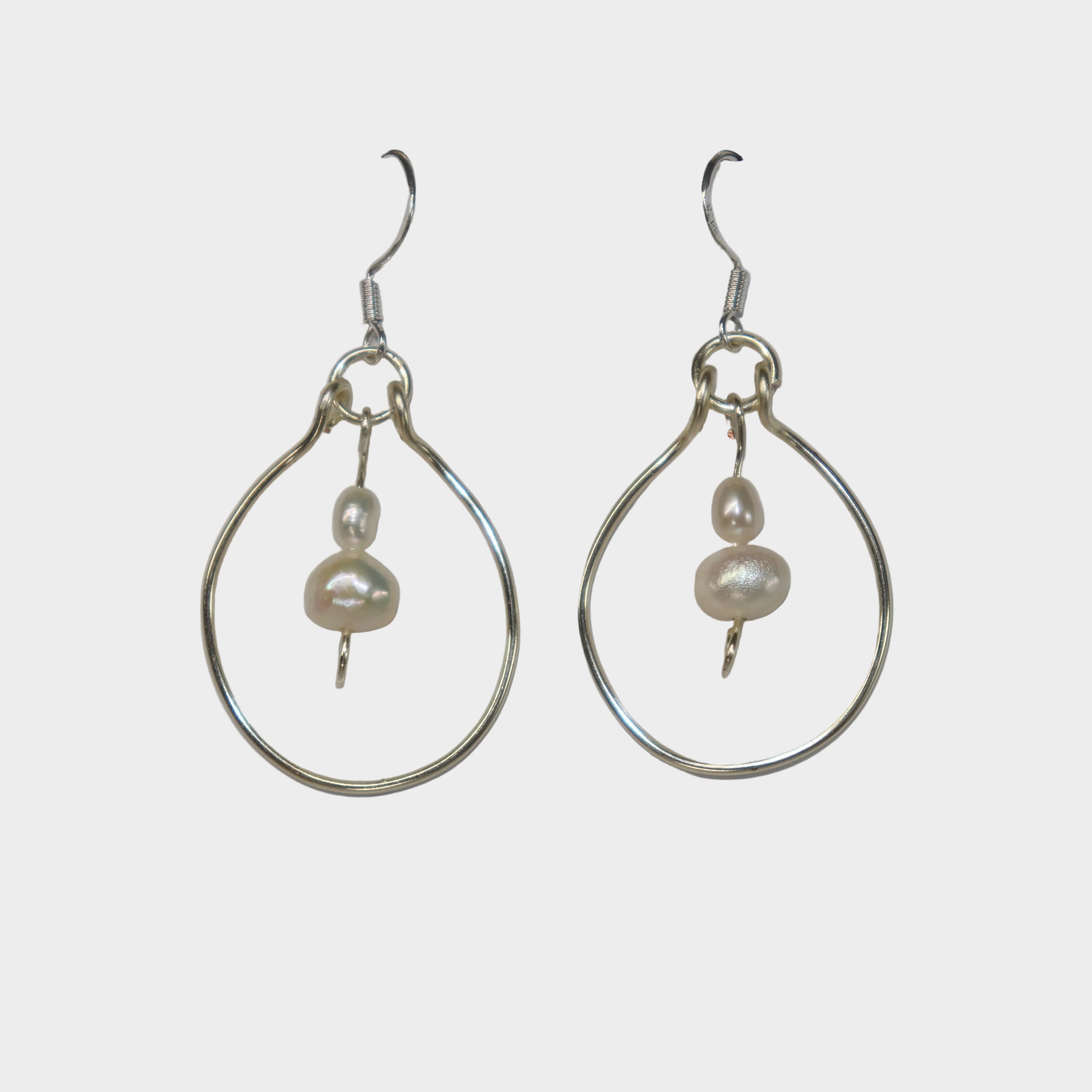 Pair of handmade silver hoop earrings with pearls on a light gray background