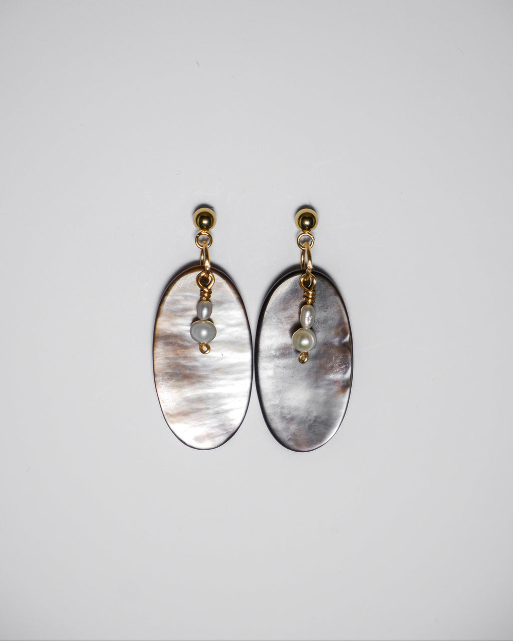 A gold earrings with pearl and an oval-shaped abalone mother of pearl on a white background.