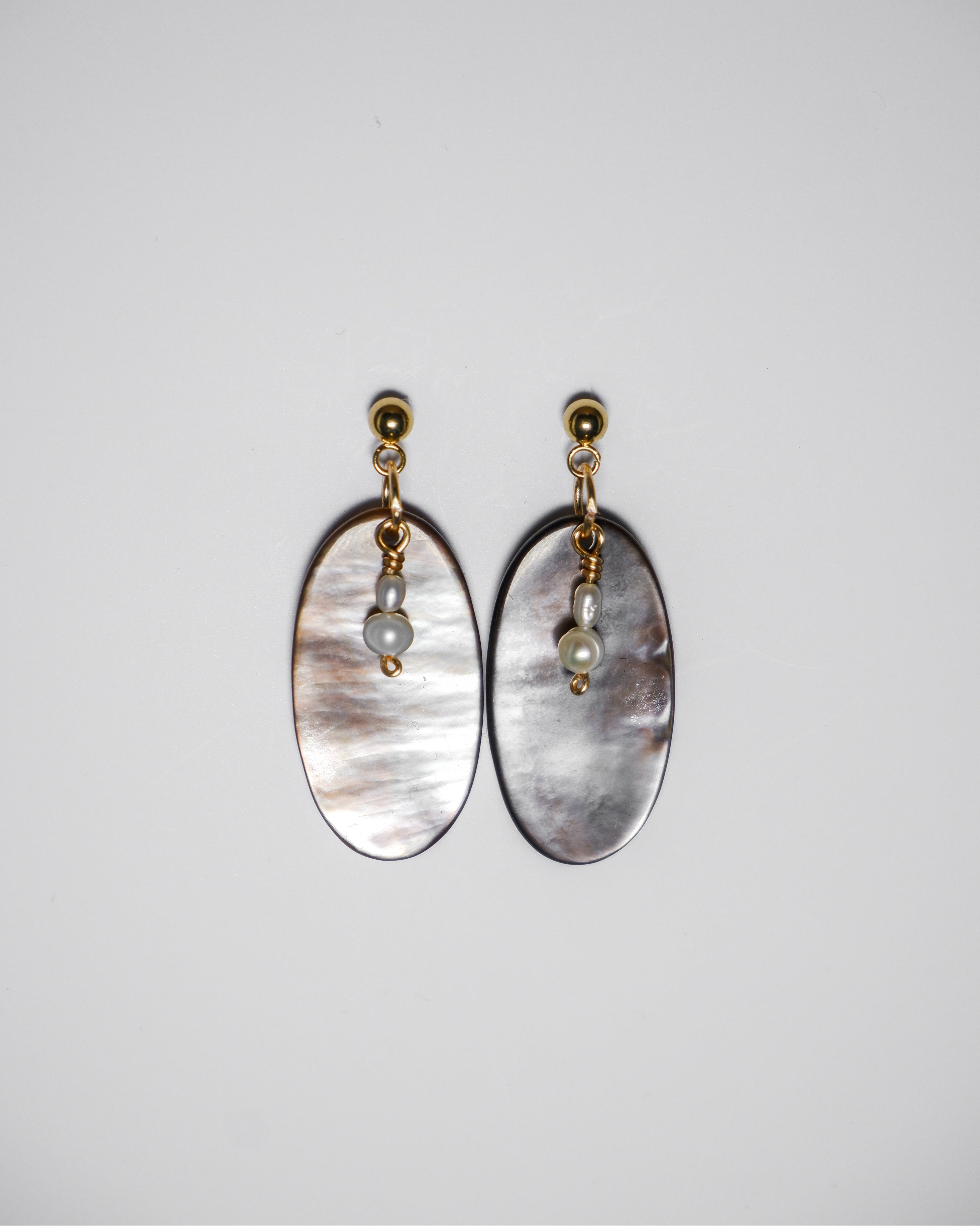 A gold earrings with pearl and an oval-shaped abalone mother of pearl on a white background.