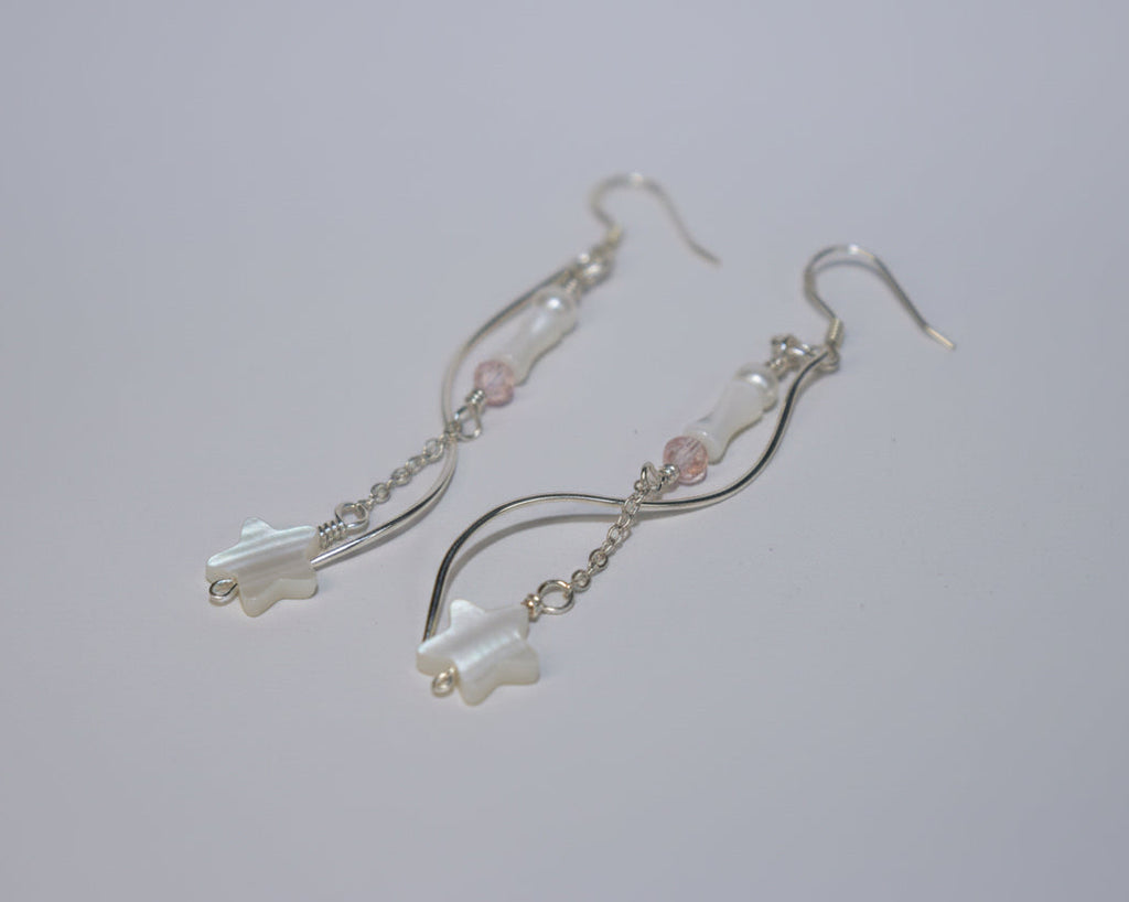 Pair of silver earrings with star-shaped charms on a white surface