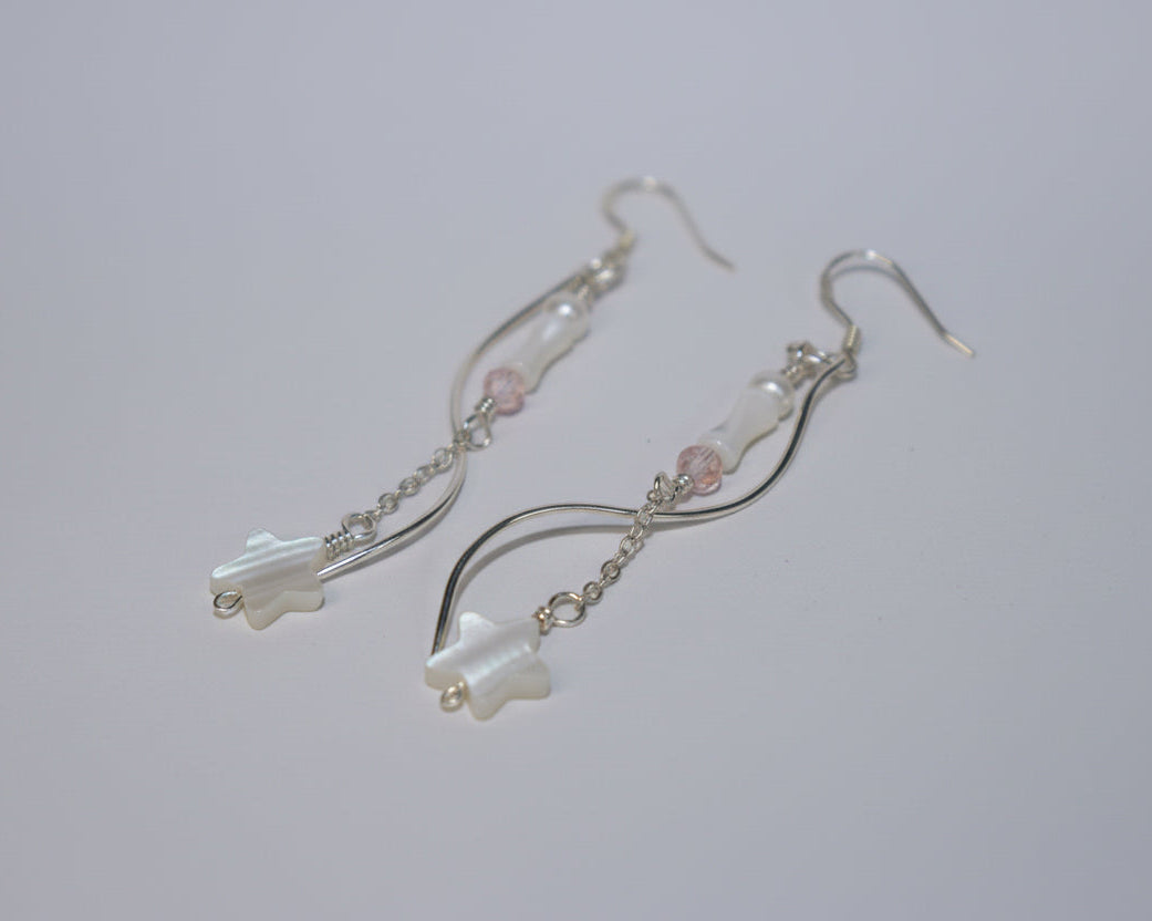 Pair of silver earrings with star-shaped charms on a white surface
