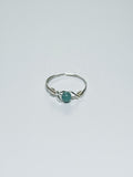 Silver wrapped ring with a green stone on a light gray background