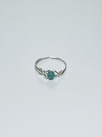 Silver wrapped ring with a green stone on a light gray background