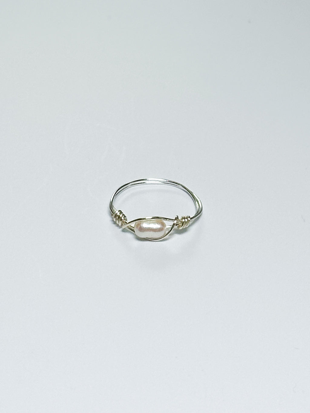 Silver ring with a pearl on a light gray background