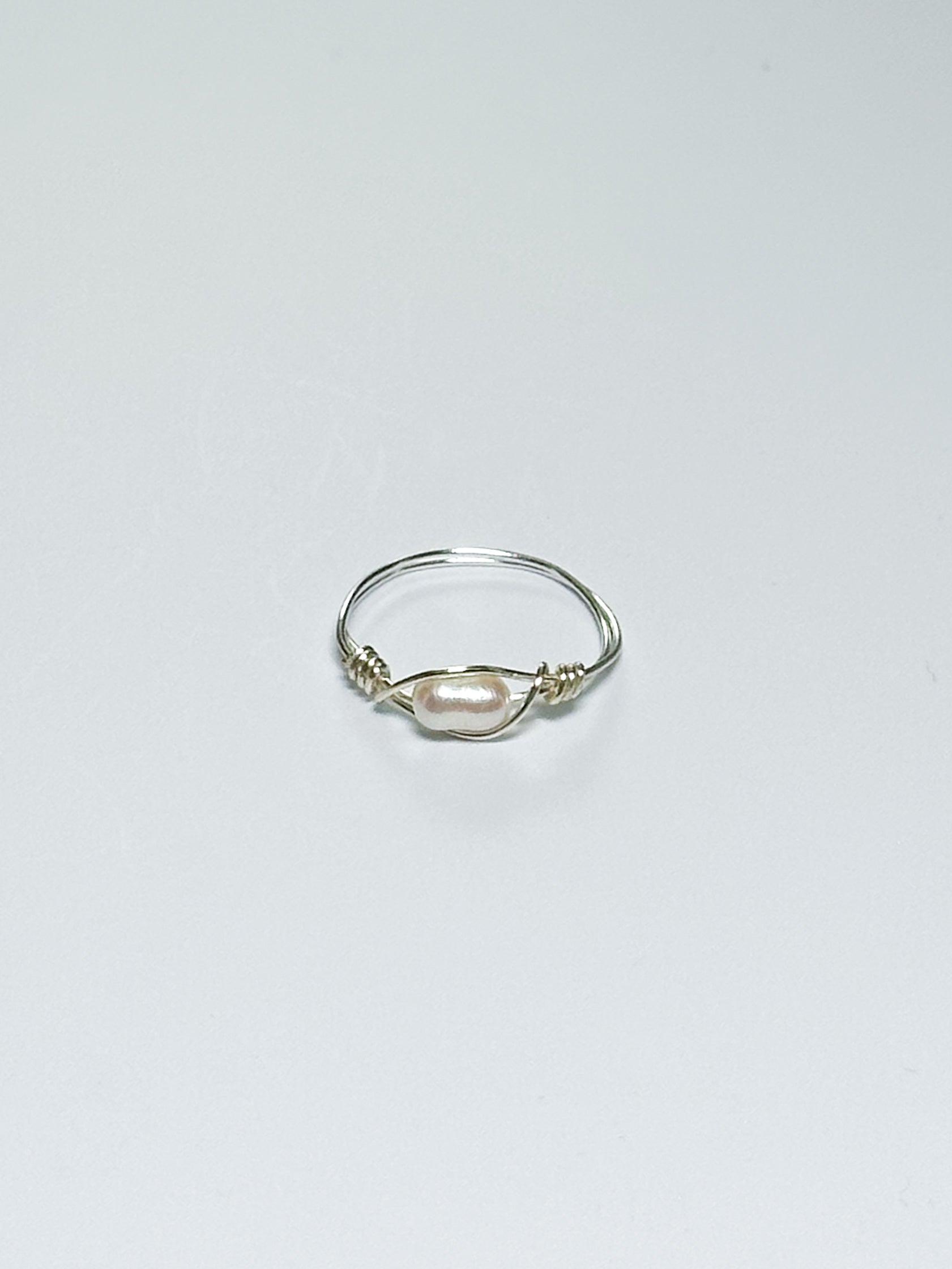 Silver ring with a pearl on a light gray background