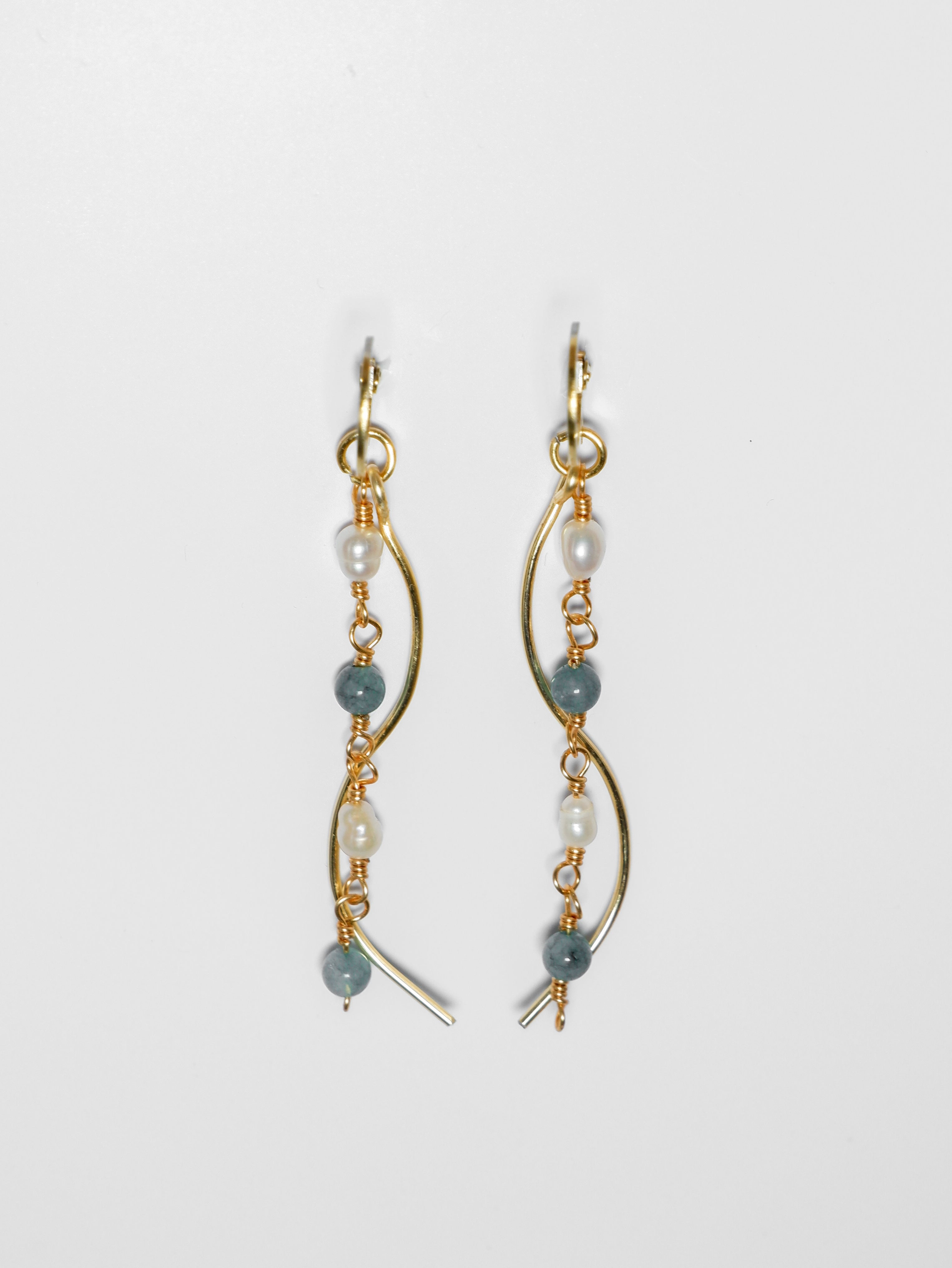 Gold pearl earrings with two bodies–one with jade blue stones and pearls linked by hooks, another is a curvy gold-plated body, on a white background and studio backdrop.